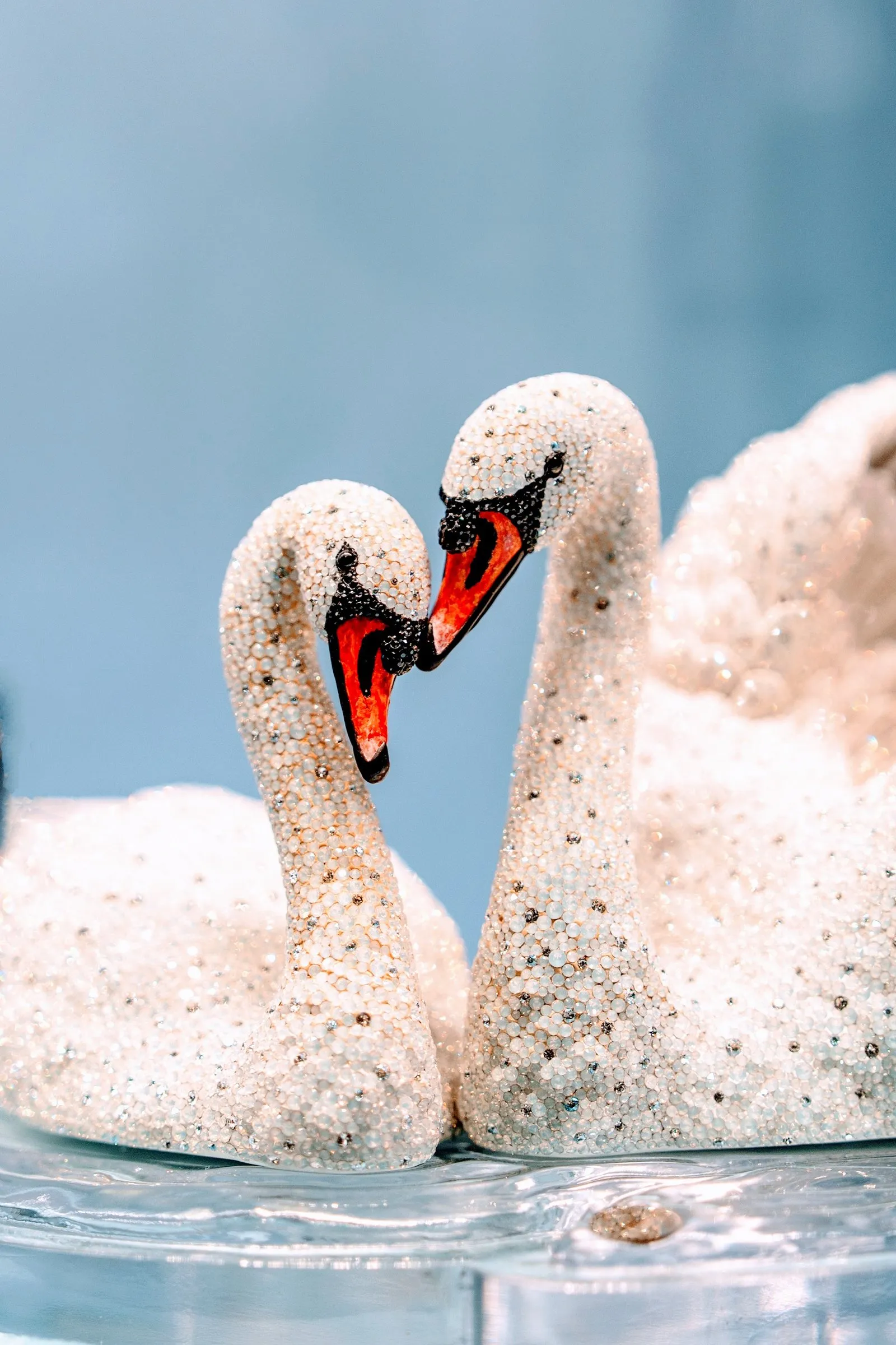 Two crystal swans facing each other, beaks touching