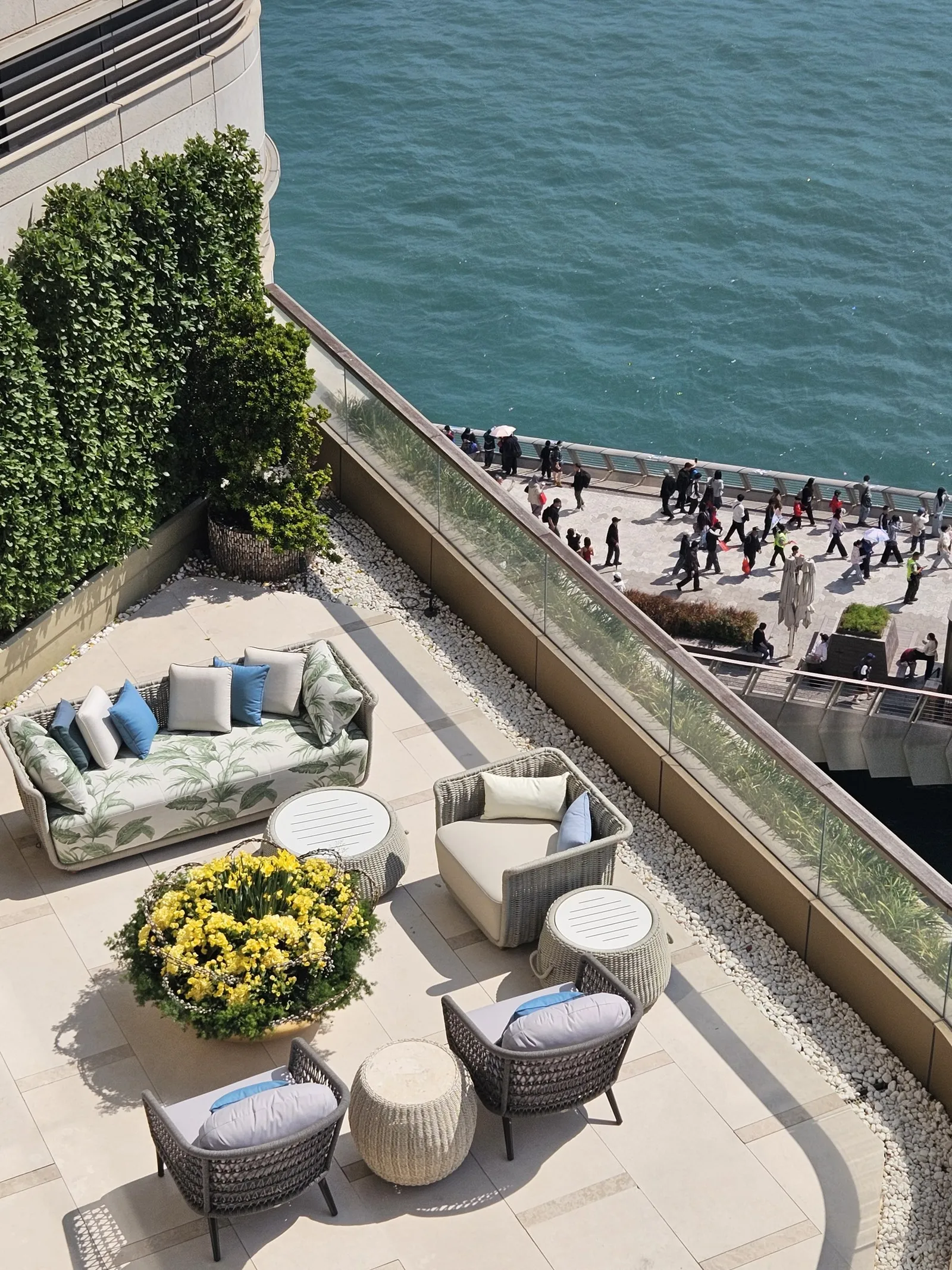 A terrace above a crowded harbourfront promenade