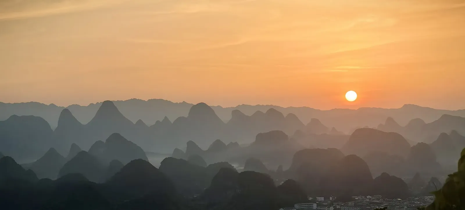Sun setting behind layered karst peaks
